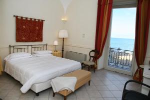 a bedroom with a bed and a view of the ocean at Palazzetto Florio 1810 in Santa Maria di Castellabate