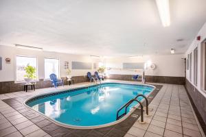 una piscina en una habitación de hotel con sillas y mesas en American inn and suites en Galesburg