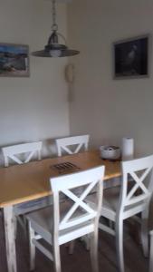 a dining room table with white chairs and a light fixture at Résidence Marie Galante Locmaria avec piscine in Locmaria