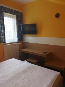 a bedroom with a bed and a desk and a television at Pri štorklji in Moravske Toplice