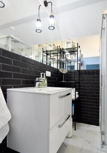 ウケンチンにあるChill&Sunの白い洗面台と黒い壁のバスルーム
