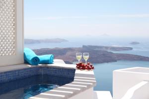 una piscina con 2 copas de vino en Whitedeck Santorini, en Imerovigli