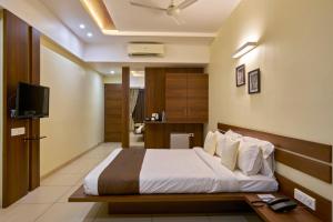 una camera d'albergo con letto e TV di Hotel 3 Leaves a Kolhapur