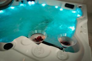 two wine glasses in front of a swimming pool at Via Aetcal Hotel & Wellness in Santiago de Compostela