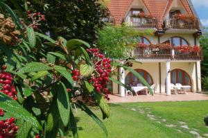 a house with a tree with red berries in front of it at Ágnes Hotel in Hévíz