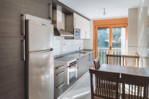 a kitchen with a stainless steel refrigerator and a table at APARTAMENTOS CASAS NOVAS in Silleda