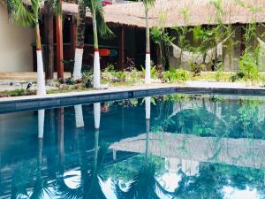 a swimming pool in front of a house with palm trees at Tierra Maya Hotel Spa & Sanctuary in Bacalar