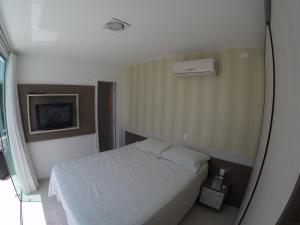 a bedroom with a white bed and a window at Apartamento Cobertura Duplex in Bombinhas