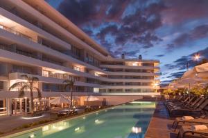 a hotel with a swimming pool in front of a building at Dos Orillas Monoambiente 412 in Colonia del Sacramento