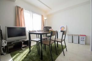 ein Wohnzimmer mit einem Tisch, Stühlen und einem TV in der Unterkunft Sannand / Vacation STAY 2188 in Sapporo