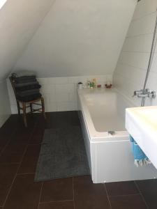 ein Badezimmer mit einer Badewanne, einem Waschbecken und einem Stuhl in der Unterkunft Helle und ruhige Dachgeschosswohnung in München