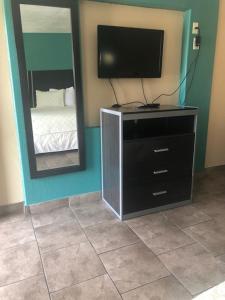 a television on a dresser in a room with a mirror at Pinn Road Inn and Suites Lackland AFB and Seaworld in San Antonio