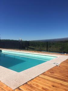 una piscina de agua azul y una terraza de madera en Gran Cabaña en Villa Yacanto en Villa Yacanto
