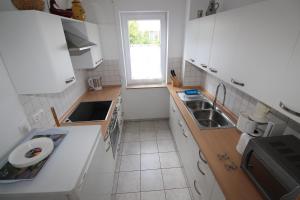 a kitchen with white cabinets and a sink and a window at Mühlgarten in Immenstaad am Bodensee