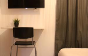 アリカンテにあるTRAVELLER EL POSTIGUETの壁にテレビと椅子が備わる客室です。