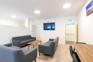 una sala de espera con sillas, mesa y TV en Hobson Lodge, en Auckland