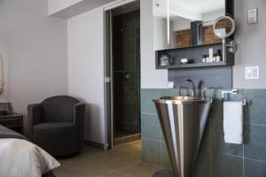 a bathroom with a sink and a chair at Hotel le Priori in Quebec City