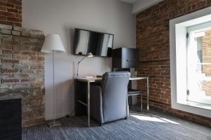 a desk with a chair and a television on a brick wall at Hotel le Priori in Quebec City