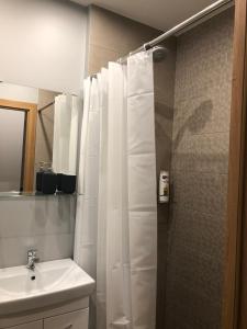 a bathroom with a white shower curtain and a sink at K&P Apartment in Vilnius