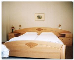 セルヴァ・ディ・ヴァル・ガルデーナにあるGarni Martlhofのベッドルーム(木製ベッド1台、ドレッサー付)