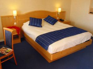 ein Schlafzimmer mit einem großen Bett mit blauen Kissen in der Unterkunft Hotel Anjou à L'Océane Angers-Le Mans in Saint-Sylvain-dʼAnjou