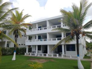 un edificio blanco con palmeras delante en Apartamentos Las Múcuras, en Coveñas