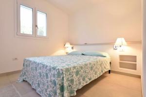 a bedroom with a bed with a blue blanket and two windows at VILLA MILVIO con accesso privato in spiaggia in Tortolì