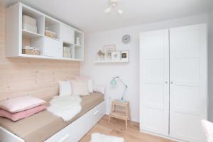 a small bedroom with white cabinets and a bench with pink pillows at Apartament Trójmiejski Park Krajobrazowy in Gdańsk