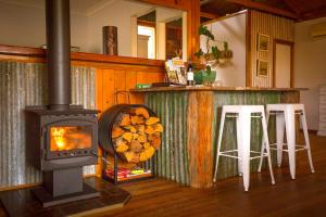 een houtkachel in een keuken met 2 krukken bij Peppercorn Cabin in Broke