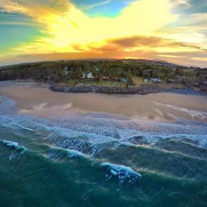 an aerial view of a beach at sunset at ABSOLUTE BEACH FRONT MACKAY - Blue Pacific in Mackay