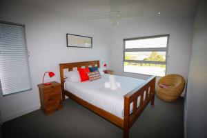 a bedroom with a bed and a chair and two windows at Pindara in Broke