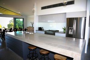 a large kitchen with a large counter with stools at Pindara in Broke