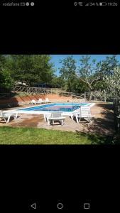 a swimming pool with three white benches next to it at Cabañas rurales la vega in Burunchel