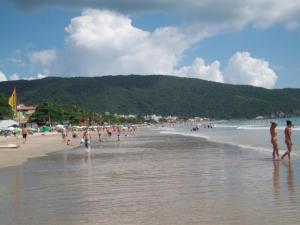 a group of people standing on a beach at Apto 2 quartos no centro de Bombinhas, 130 metros praia in Bombinhas