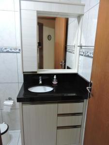 a bathroom with a sink and a mirror at Apto 2 quartos no centro de Bombinhas, 130 metros praia in Bombinhas