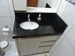 a bathroom with a sink and a mirror and a toilet at Apto 2 quartos no centro de Bombinhas, 130 metros praia in Bombinhas +33 photos
