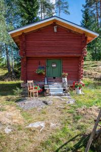a red cabin with a green door and a chair at Villa Vuorenpää in Tammela