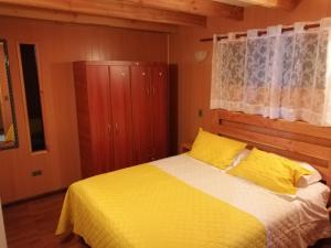 1 dormitorio con 1 cama con sábanas amarillas y ventana en Cabañas los Ulmos, en Pucón