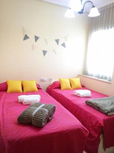 2 Betten in einem Zimmer mit rosa Bettwäsche und gelben Kissen in der Unterkunft Junto PLAYA, Gemelos 23 con 2 baños Excelente opcion in Benidorm + 37 Fotos
