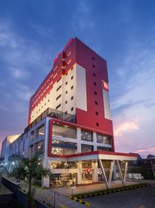 un edificio alto de color rojo con un letrero iluminado en ibis Pontianak City Center en Pontianak