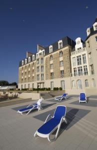 een groot gebouw met ligstoelen ervoor bij Residence Reine Marine in Saint-Malo