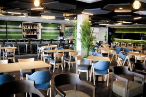 ein Restaurant mit Holztischen und blauen Stühlen in der Unterkunft Kudat Golf & Marina Resort in Kudat