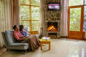 a man and woman sitting in a chair in front of a fireplace at Los Pinos Cabins & Reserve in Monteverde Costa Rica