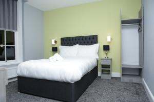 1 dormitorio con 1 cama grande con almohadas blancas en The Spring Bank APARTHOTEL, en Preston