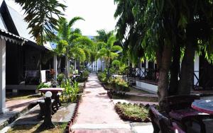 una pasarela con palmeras y bancos en una calle en Rasa Senang Villa -Islam Guest Only, en Pantai Cenang