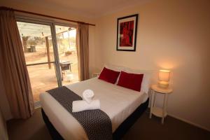 a bedroom with a bed with red pillows and a window at Verona Vineyard Cottage in Pokolbin