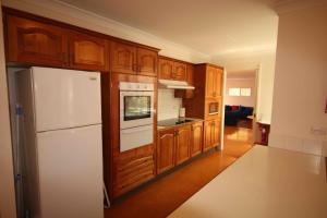 una cucina con frigorifero bianco e armadietti in legno di Verona Vineyard Cottage a Pokolbin