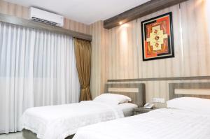 Una habitación de hotel con dos camas y un televisor. en Graha SUMSEL, en Yakarta