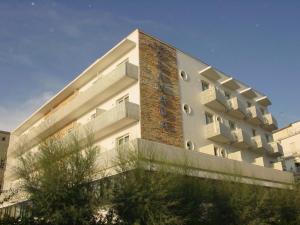 um edifício branco alto com uma parede de tijolos em Hotel Granada em Milano Marittima