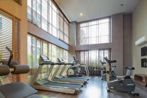 a gym with treadmills and ellipticals in a room with windows at D Condo Nernpra Rayong in Rayong